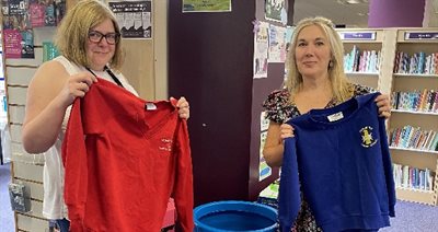 Two women holding up items of school uniform