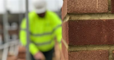 Close up of Bricks with builder bricklaying on a scaffold