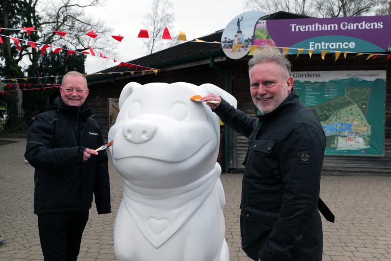 Two men stood either side of a giant white sculpture of a Staffordshire Bull Terrier called Staffy, which is the county's new visitor mascot.