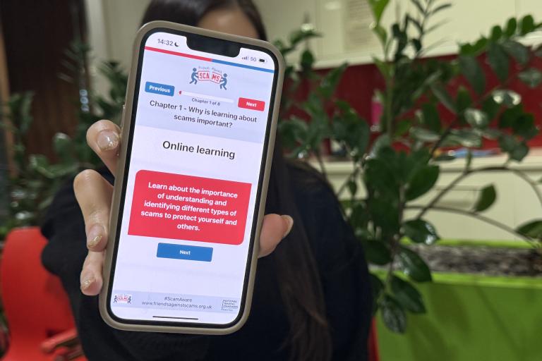 Talia holding up phone with Friends Against Scams website