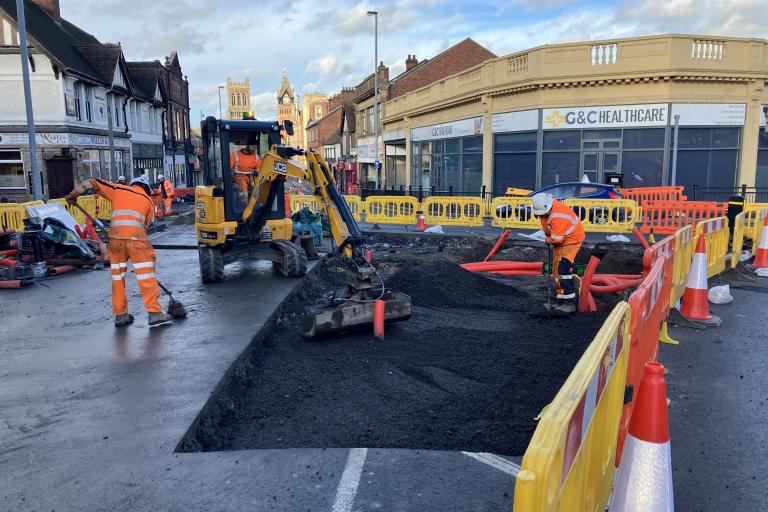 Highways crews in orange high vis uniform working on a road.