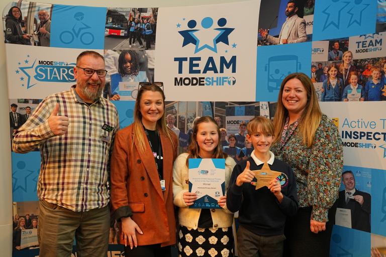 Ryan Procter, Connectivity Project Support Officer at Staffordshire County Council, with Jess Brown, Lauren Marshall-Gee and two of the Active Travel Ambassadors from Outwoods Primary School, Burton as they receive their National Primary School Of The Year award at the Modeshift Annual National Travel Awards.