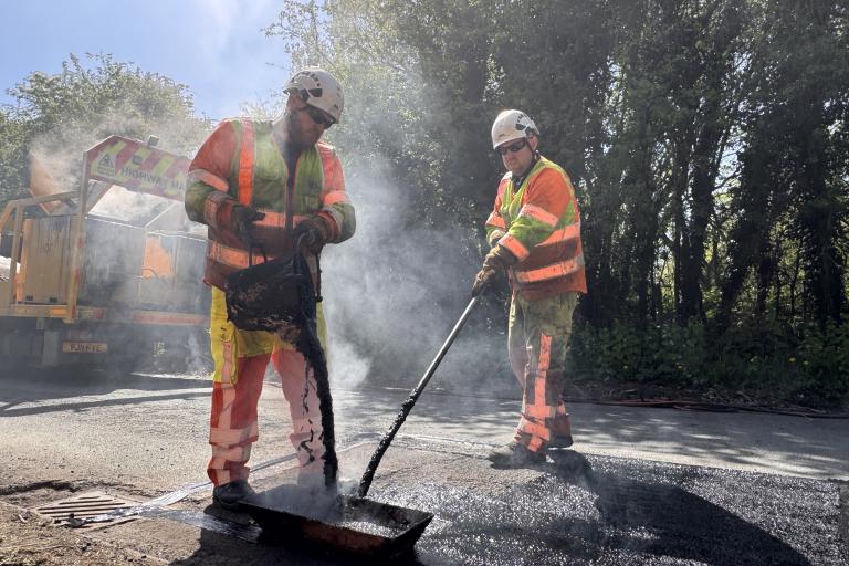 Two highways workers repairing a road