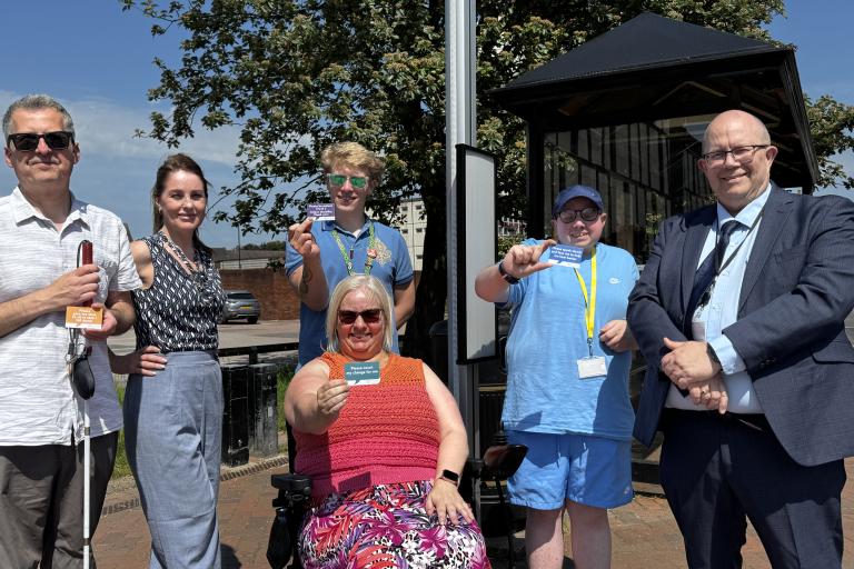 Martin Rogerson with members of campaign with travel assistance cards at a bus stop