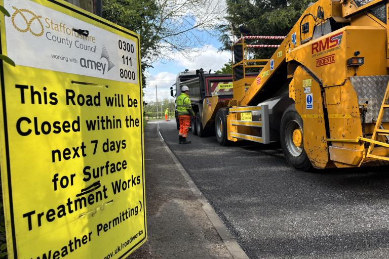 A picture of a yellow surface dressing sign, next to a newly surfaced road
