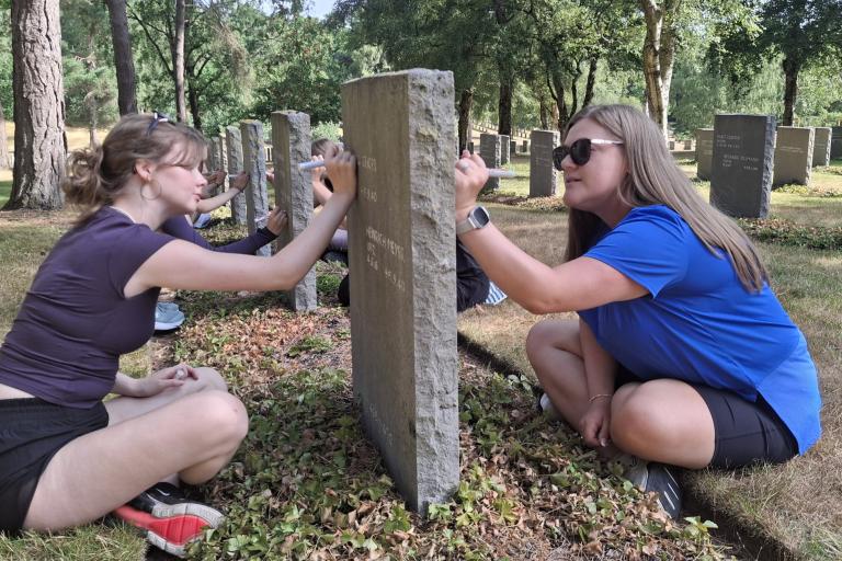 Teenagers tending to graves with trees surrounding them