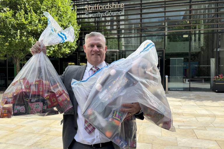 Anthony Screen holding seized squidgy toys in bags outside of county council building