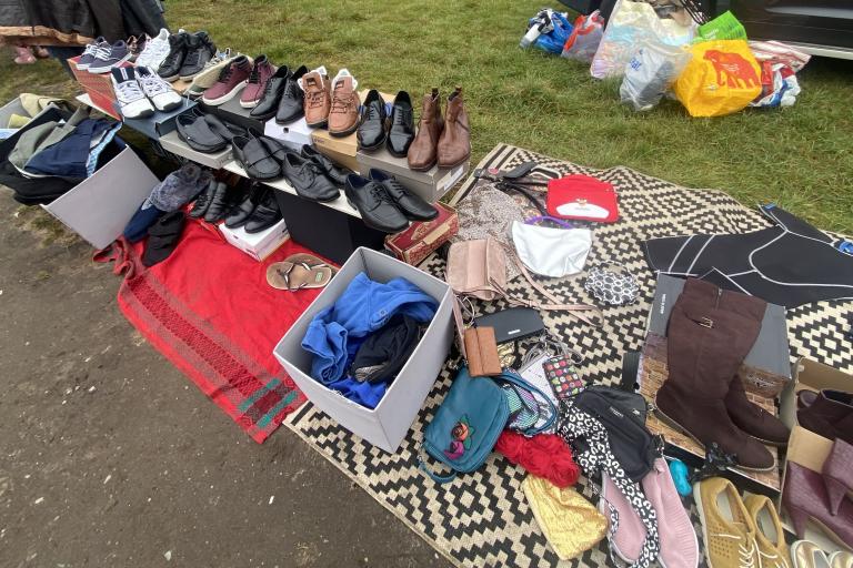 items laid out on ground at car boot sale, including shoes and clothes
