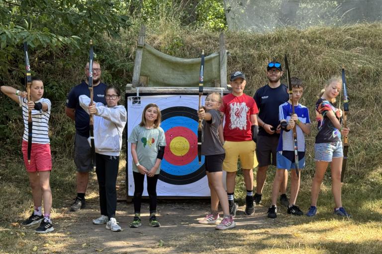 children taking part in archery activity in woods