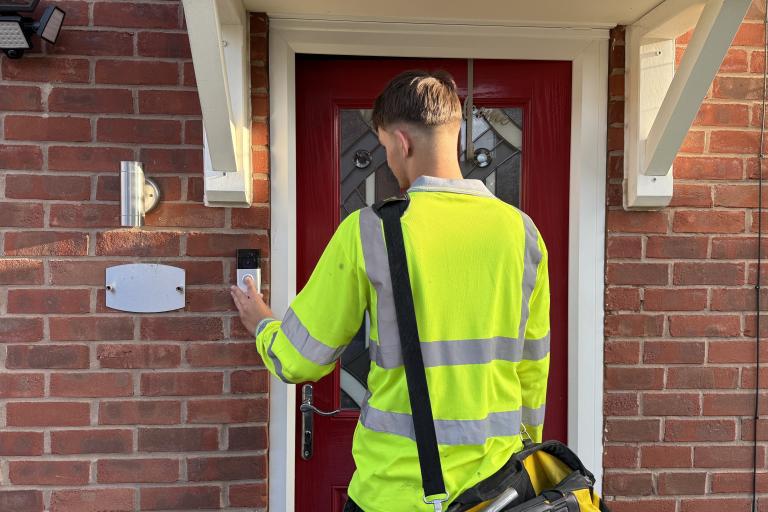 A trader in a yellow vest knocking on a front door