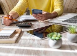 Image of person working at desk with calculator and notepad
