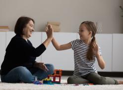 Woman and child sitting playing with blocks giving each other high five