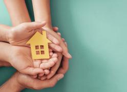 Image of hands holding a paper cut out of a house