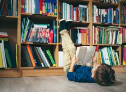 Child reading in a library surrounded by books