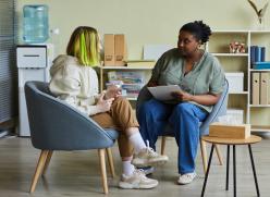 Image of adult and young person looking at a book and notepad