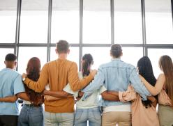 Team of 7 people standing facing a window looking to the future