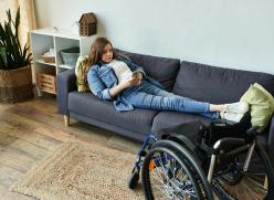 Young woman with disability relaxes in her apartment while using her smartphone