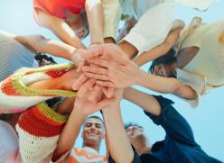 Blue sky, below and hands stack of people in circle for support, solidarity and community outdoors. Diversity, students and group of friends