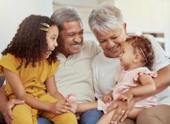 Older man and woman sitting on sofa with 2 children on their knee