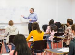 teacher stood at a whiteboard in front of students