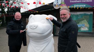 Two men stood either side of a giant white sculpture of a Staffordshire Bull Terrier called Staffy, which is the county's new visitor mascot.