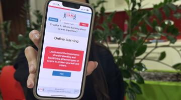 Talia holding up phone with Friends Against Scams website