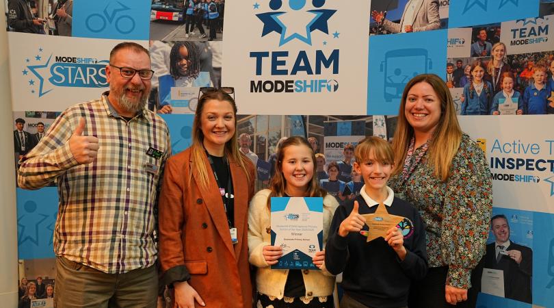 Ryan Procter, Connectivity Project Support Officer at Staffordshire County Council, with Jess Brown, Lauren Marshall-Gee and two of the Active Travel Ambassadors from Outwoods Primary School, Burton as they receive their National Primary School Of The Year award at the Modeshift Annual National Travel Awards.