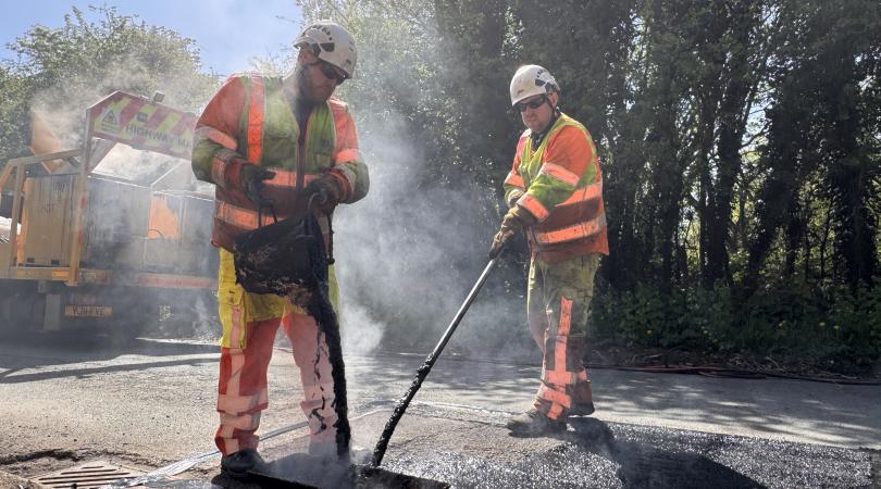 Two highways workers repairing a road