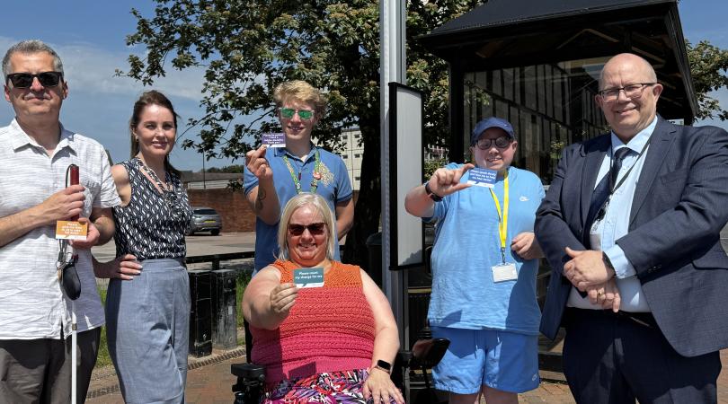 Martin Rogerson with members of campaign with travel assistance cards at a bus stop