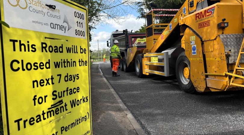 A picture of a yellow surface dressing sign, next to a newly surfaced road