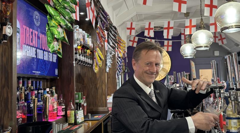 Martin Murray pouring a pint with World Cup England flag bunting above