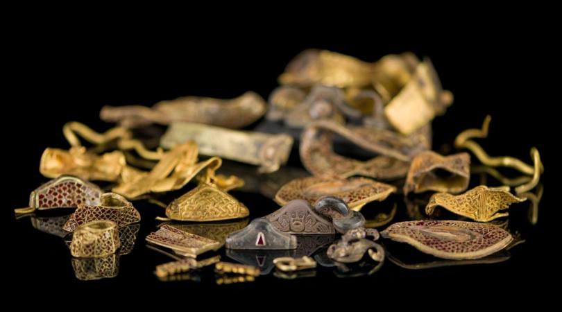 A collection of Anglo-Saxon gold and silver, including sword fittings, helmet fragments and other military related items.