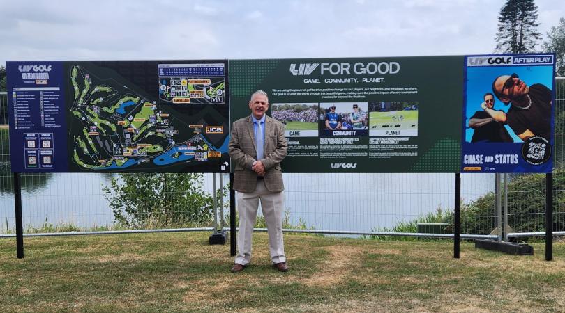 Patrick Allen next to signs promoting the LIV Golf championship event at JCB Golf and Country Club