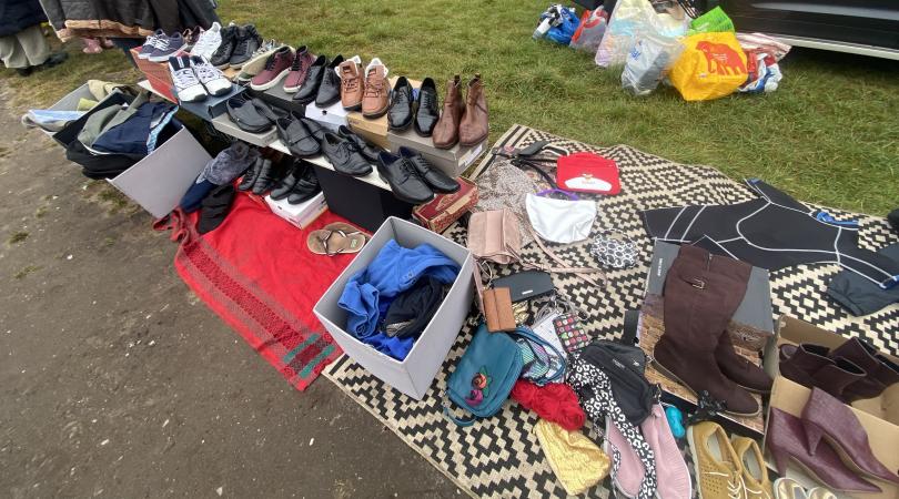 items laid out on ground at car boot sale, including shoes and clothes
