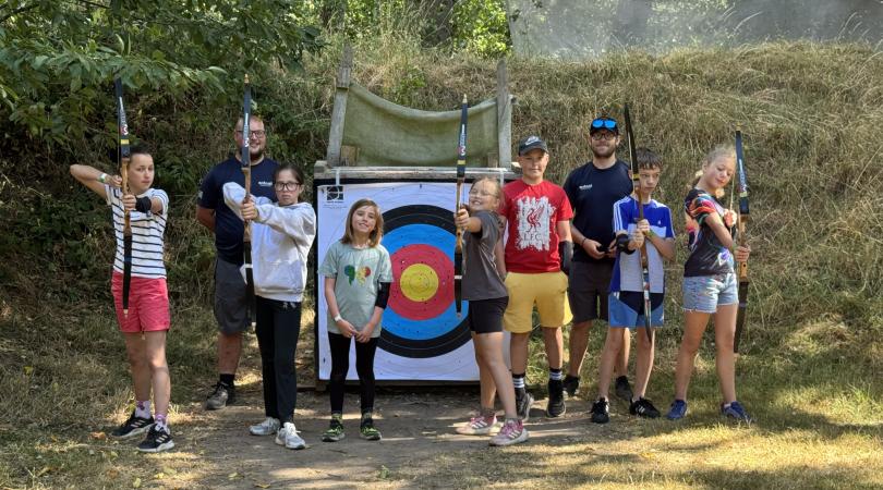 children taking part in archery activity in woods