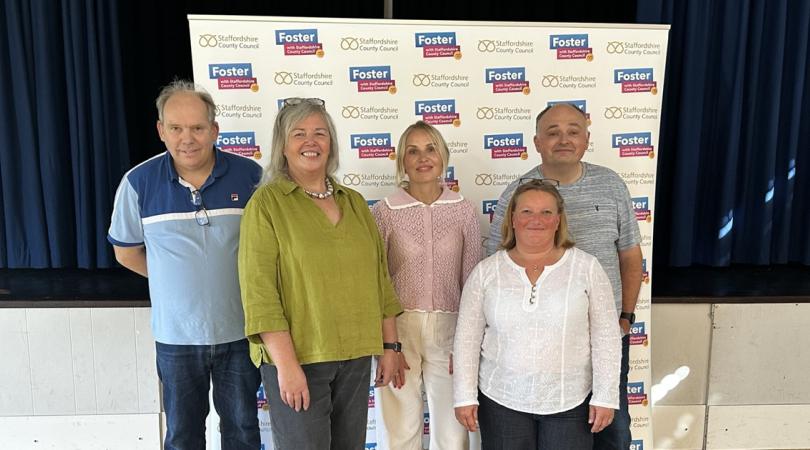Foster carers stood in front of promotional banner