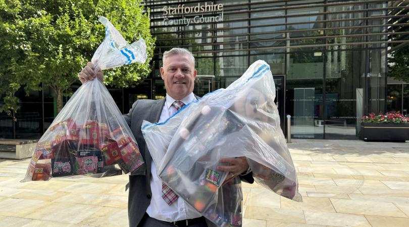 Anthony Screen holding seized squidgy toys in bags outside of county council building